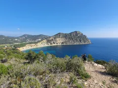 Sendero costero de Ibiza durante la 1ª Vuelta a Ibiza, con un peñón rocoso al fondo
